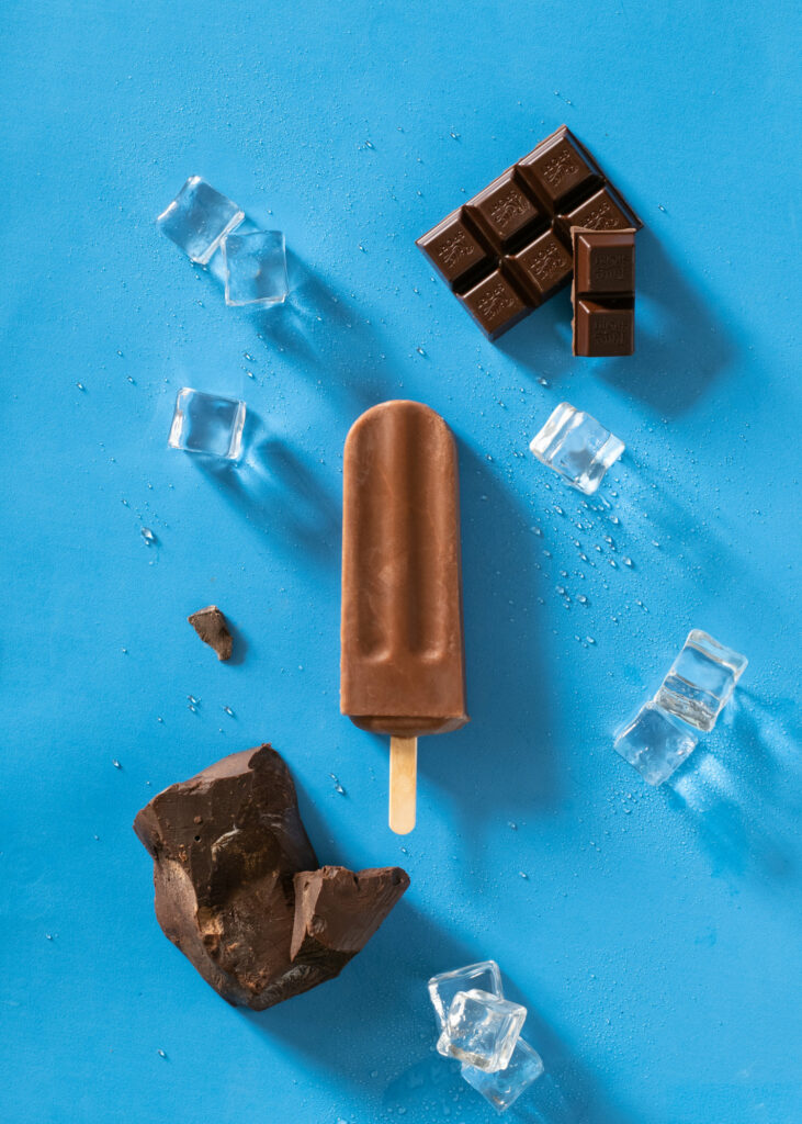 Chocolate brownie ice pop with chocolate and ice on a bright blue background